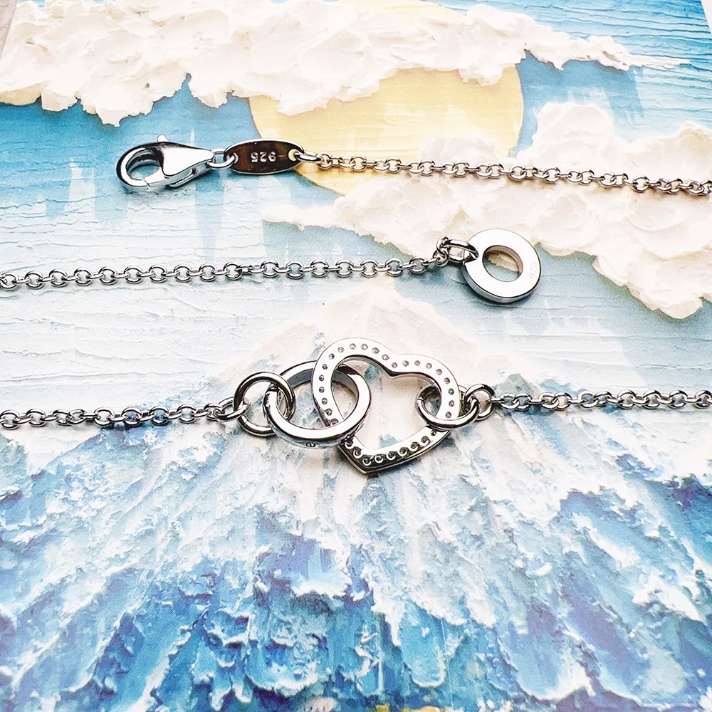 925 sterling silver necklace clasp, chain links and heart centerpiece shown on a blue surface