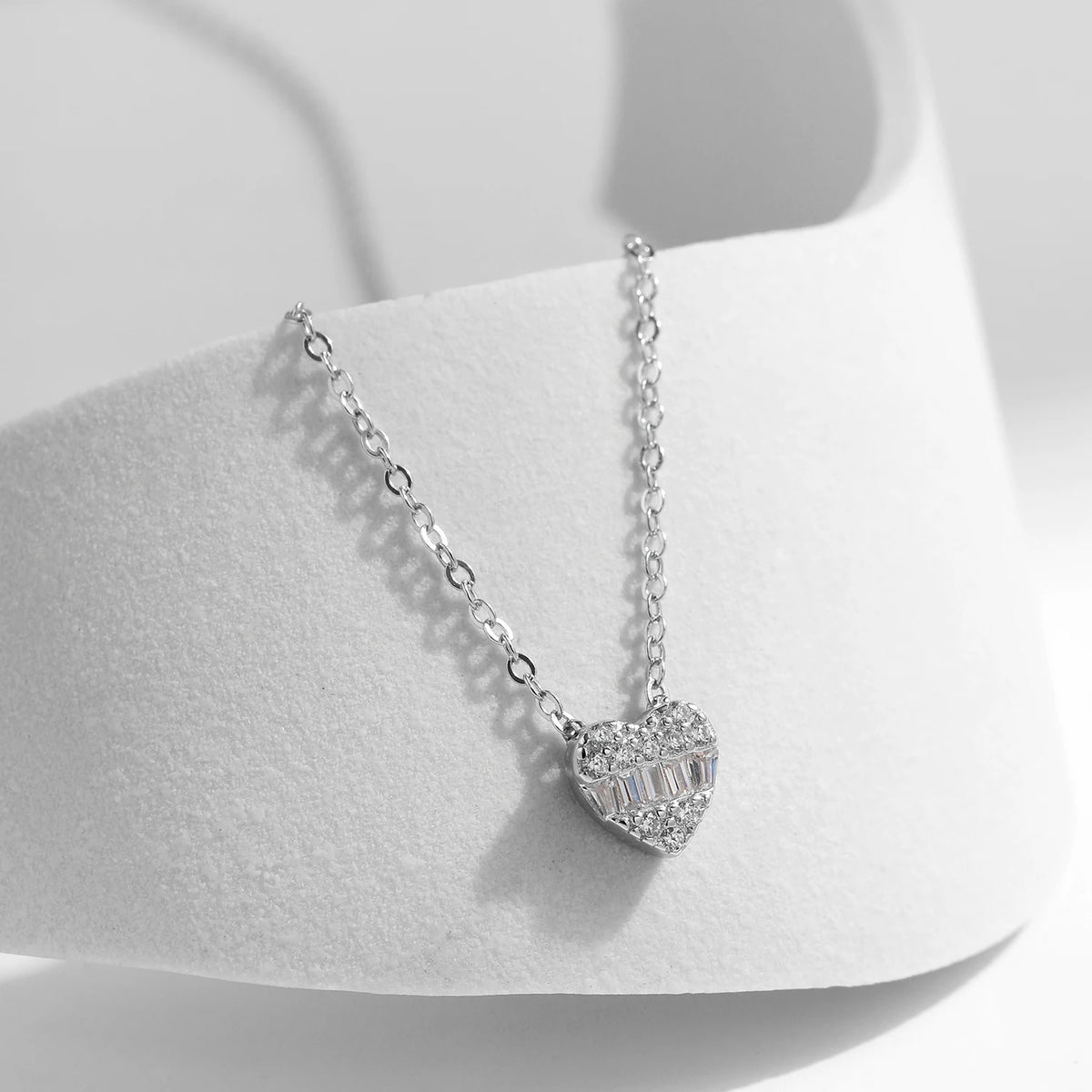 Close-up of the 925 sterling silver heart pendant with round clear stones and rectangular CZ center stones