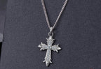 Stone-set Gothic cross pendant on a silver-tone chain against a dark textured background