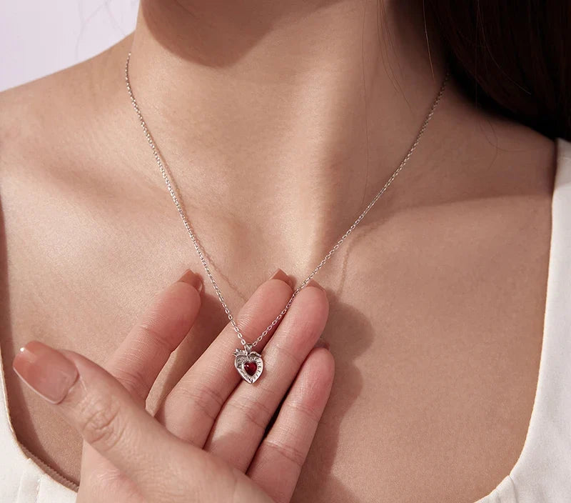 White gold-plated sterling silver strawberry heart necklace worn with the pendant held in hand