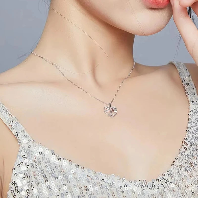 Silver-tone tree of life heart pendant worn on the neck, showing the openwork branches and heart outline