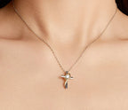 Two-tone cross pendant necklace worn on the neck, showing the gold heart loop around the center stone