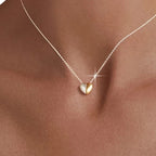 Two-tone puffed heart necklace worn at the base of the neck with a silver-tone fine chain