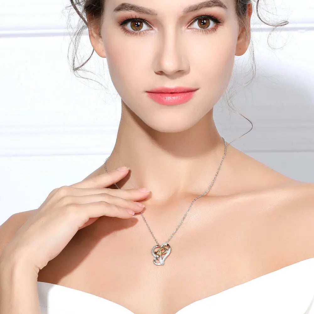 Woman wearing the two-tone hand in hand heart necklace at the collarbone with the clasped hands visible