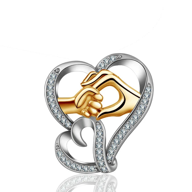 Two-tone hand in hand heart pendant with gold-colored hands and clear CZ-set silver heart curves on white